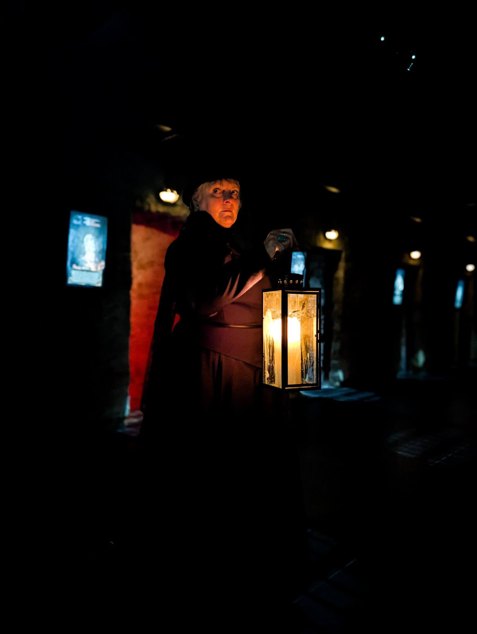 Ghost Walk guide holding a lantern in a dark corridor at Bodmin Jail
