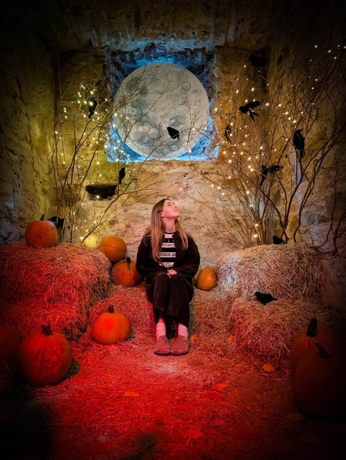 Girl sitting among pumpkins in a moonlit Halloween scene at Bodmin Jail