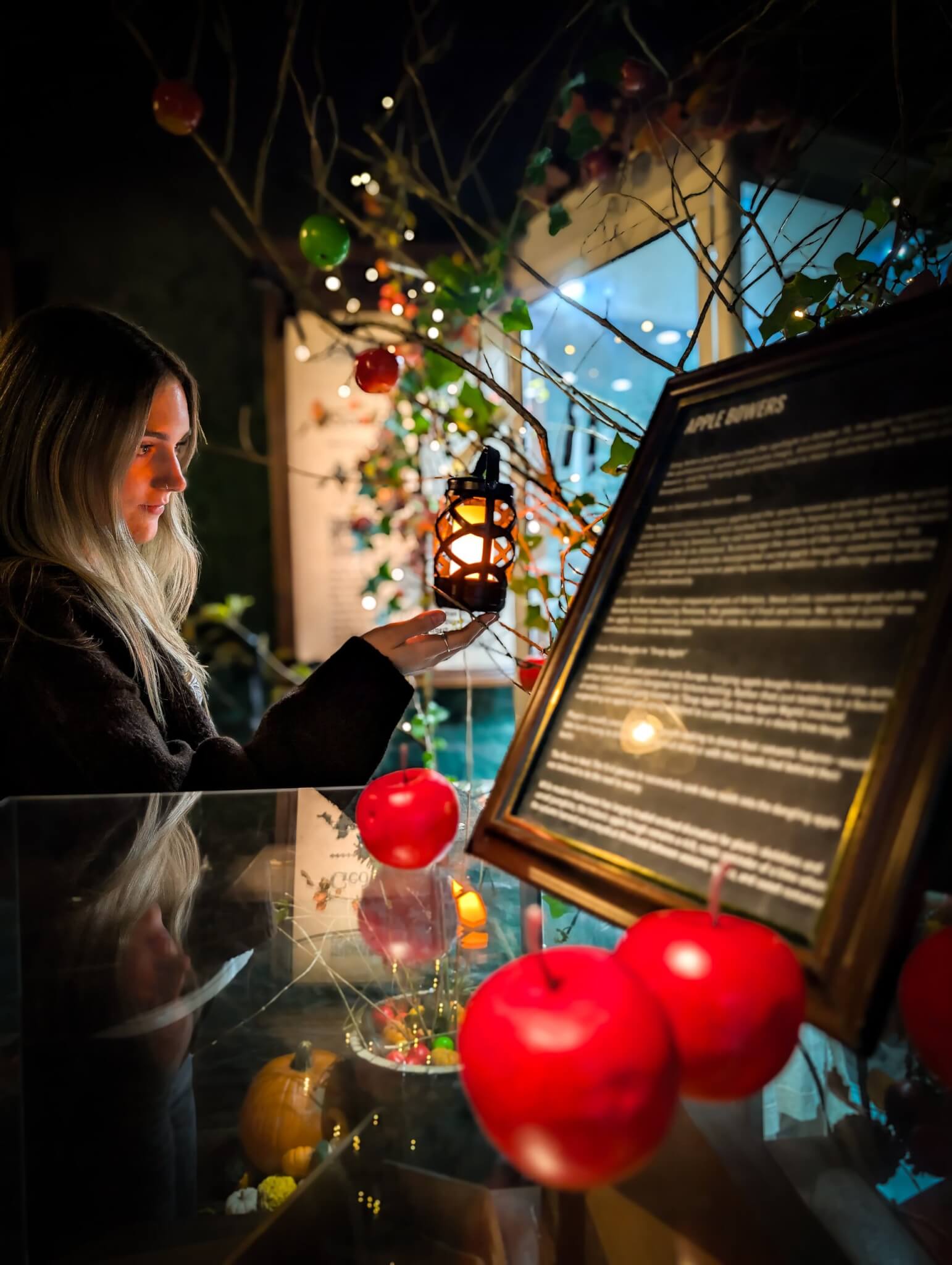 Visitor with a lantern beside red apples at Bodmin Jail