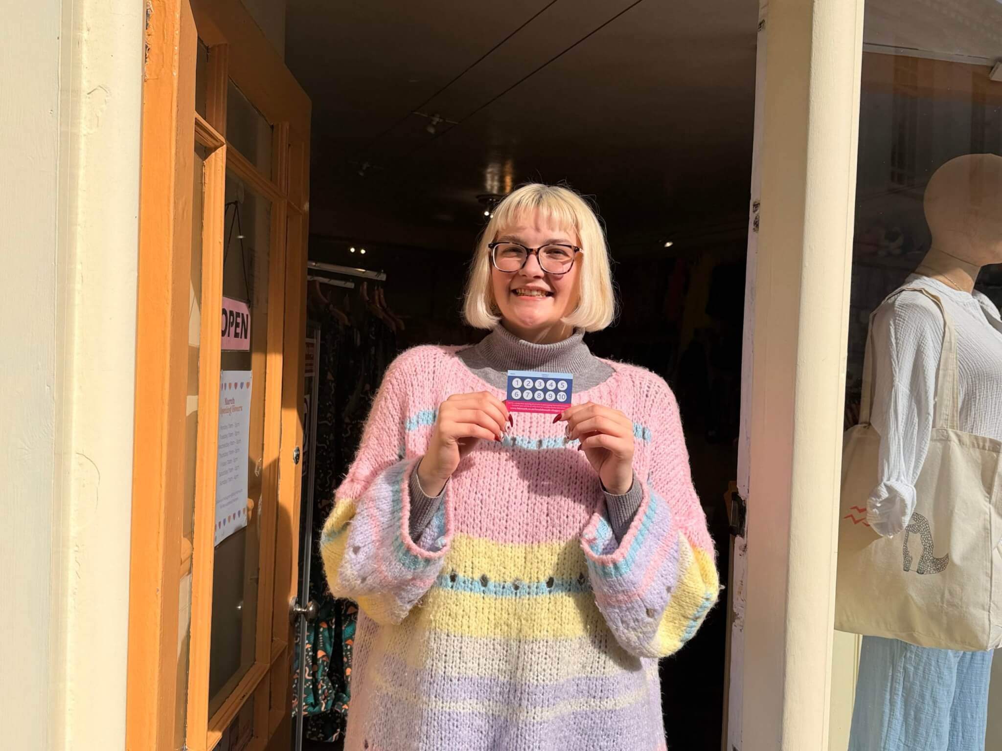Kimberley at Dizzy holding a LoveFalmouth Shopper Card in the shop doorway
