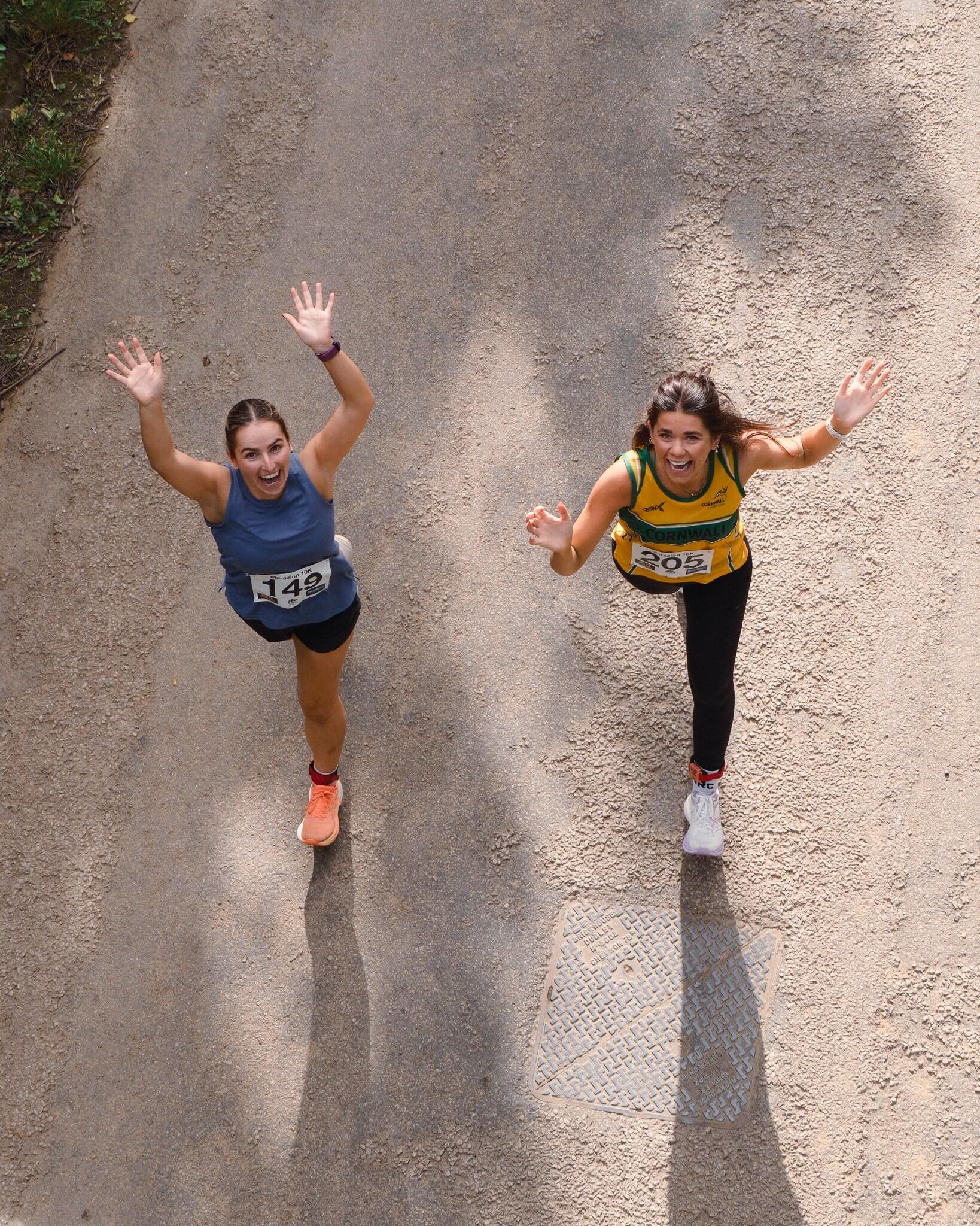 Two runners wave up at the camera during the Marazion 10K