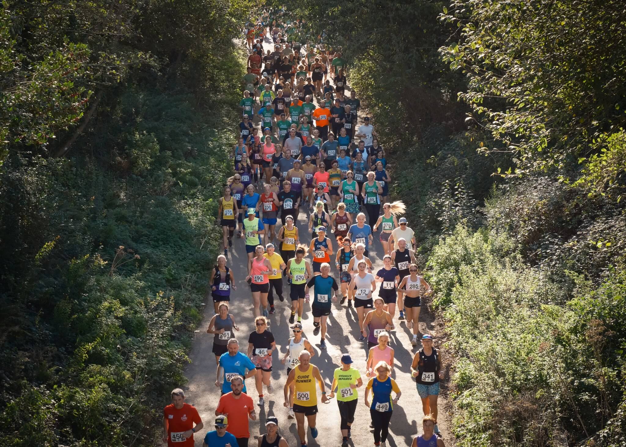Runners fill a tree-lined lane at the start of the Marazion 10K