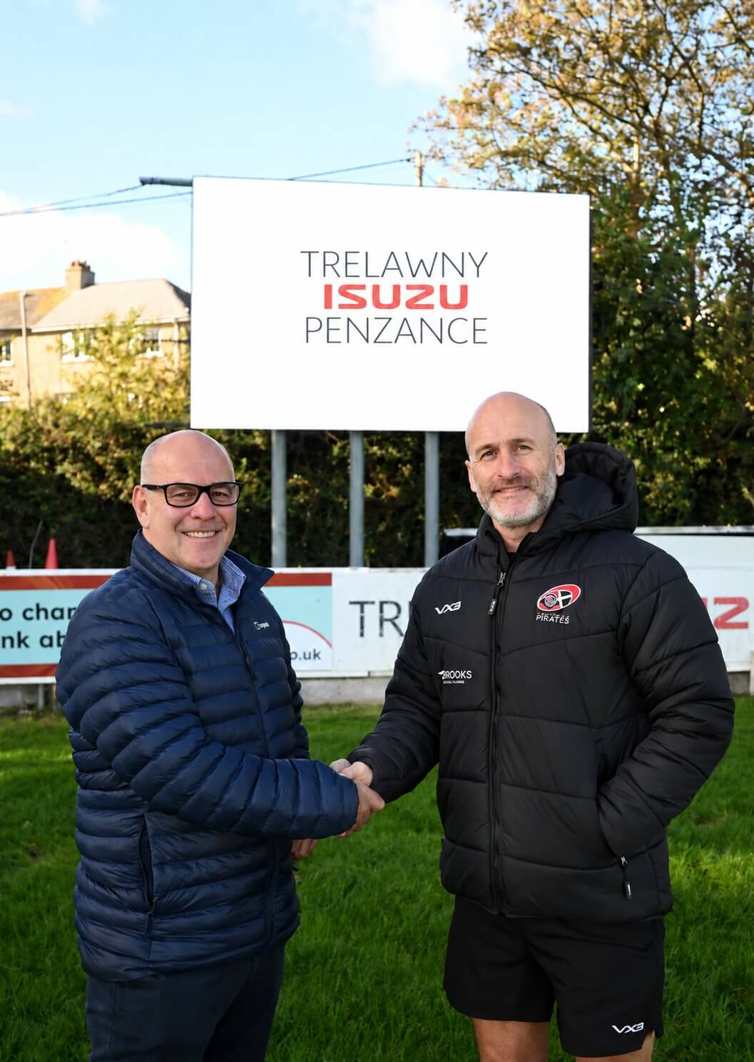 Martin Murrish and Gavin Cattle shaking hands beneath a Trelawny Isuzu Penzance sign