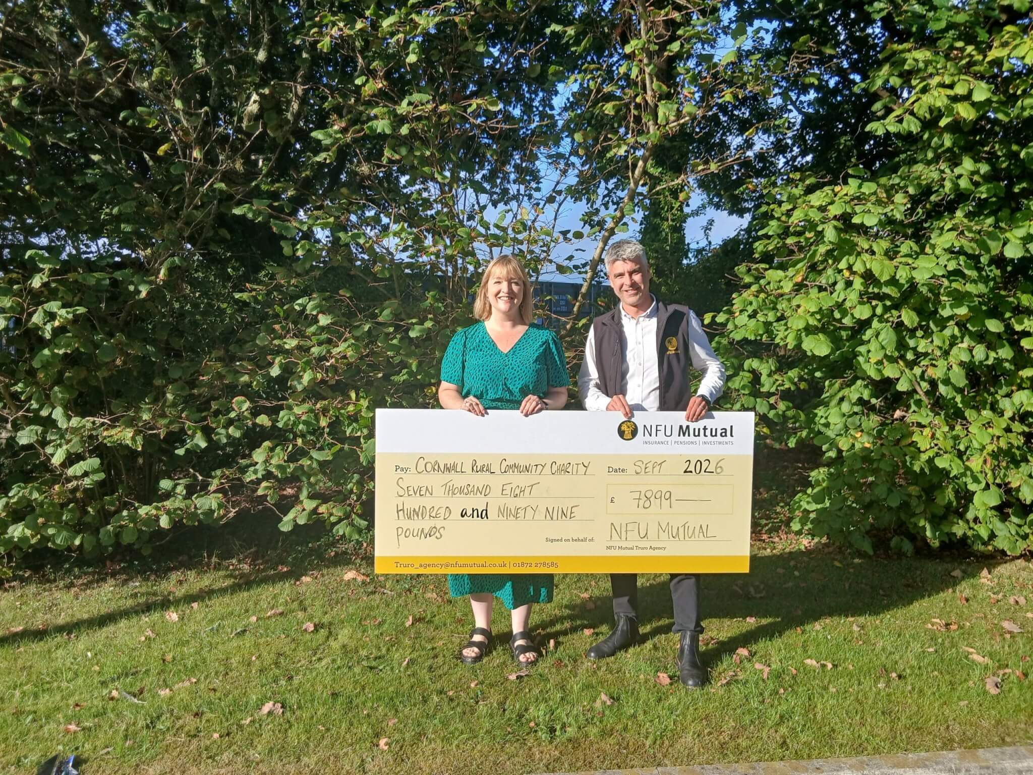 Katherine Nissen and Paul Shirley holding a large NFU Mutual cheque for £7,899 made out to Cornwall Rural Community Charity