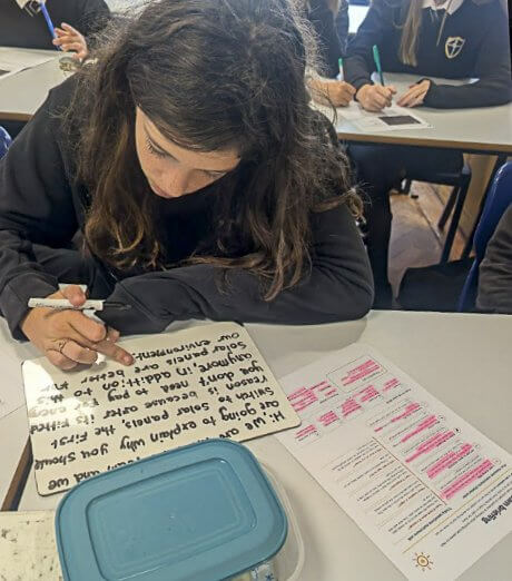 A Treviglas Academy student writing a solar sales pitch on a whiteboard