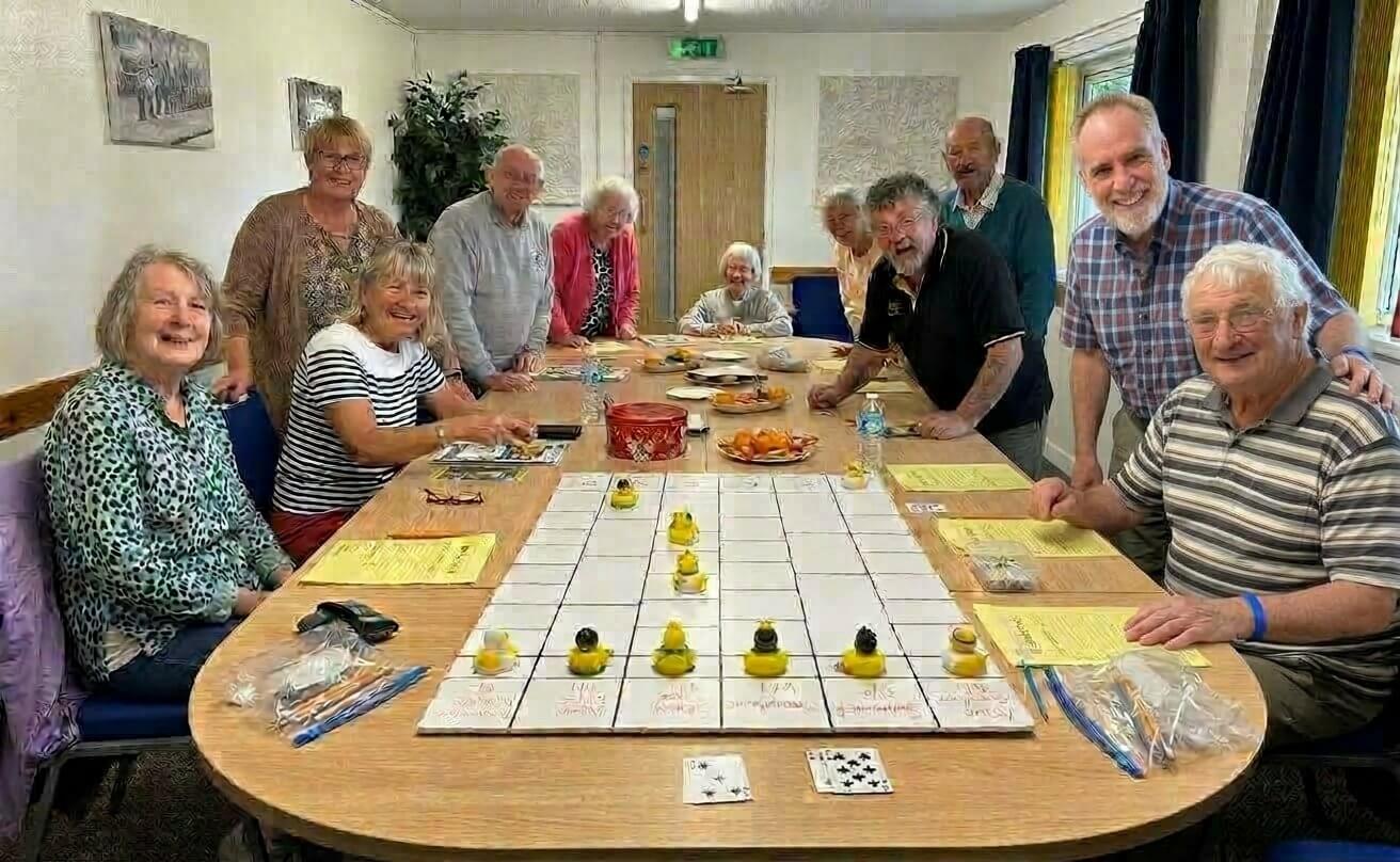 Oddfellows members smiling around a table set up for a duck race game