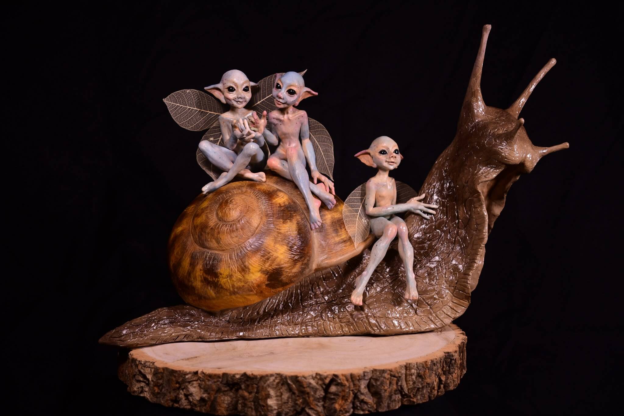 Sculpture of three small folklore figures riding a snail
