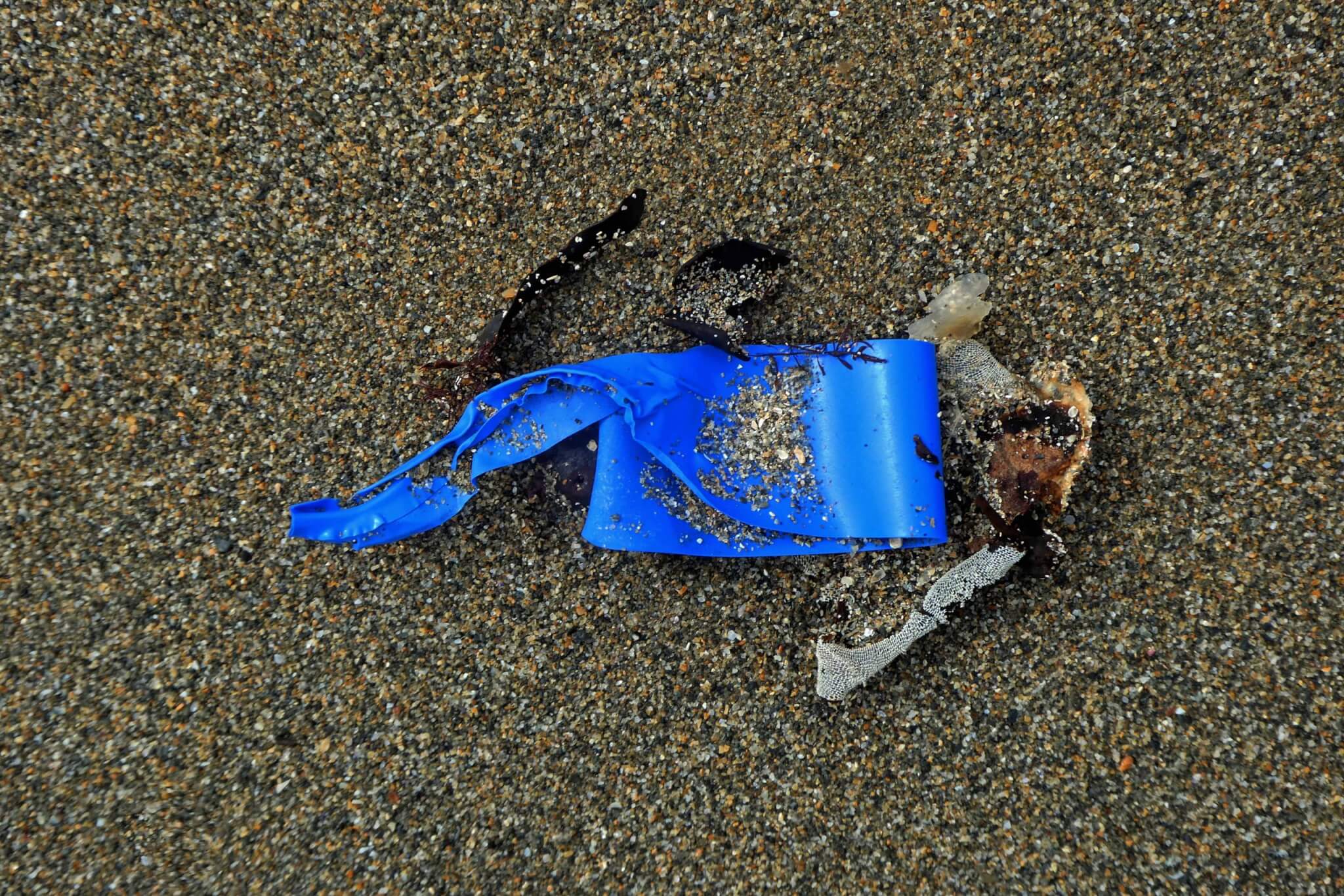 Blue plastic fragment on the sand