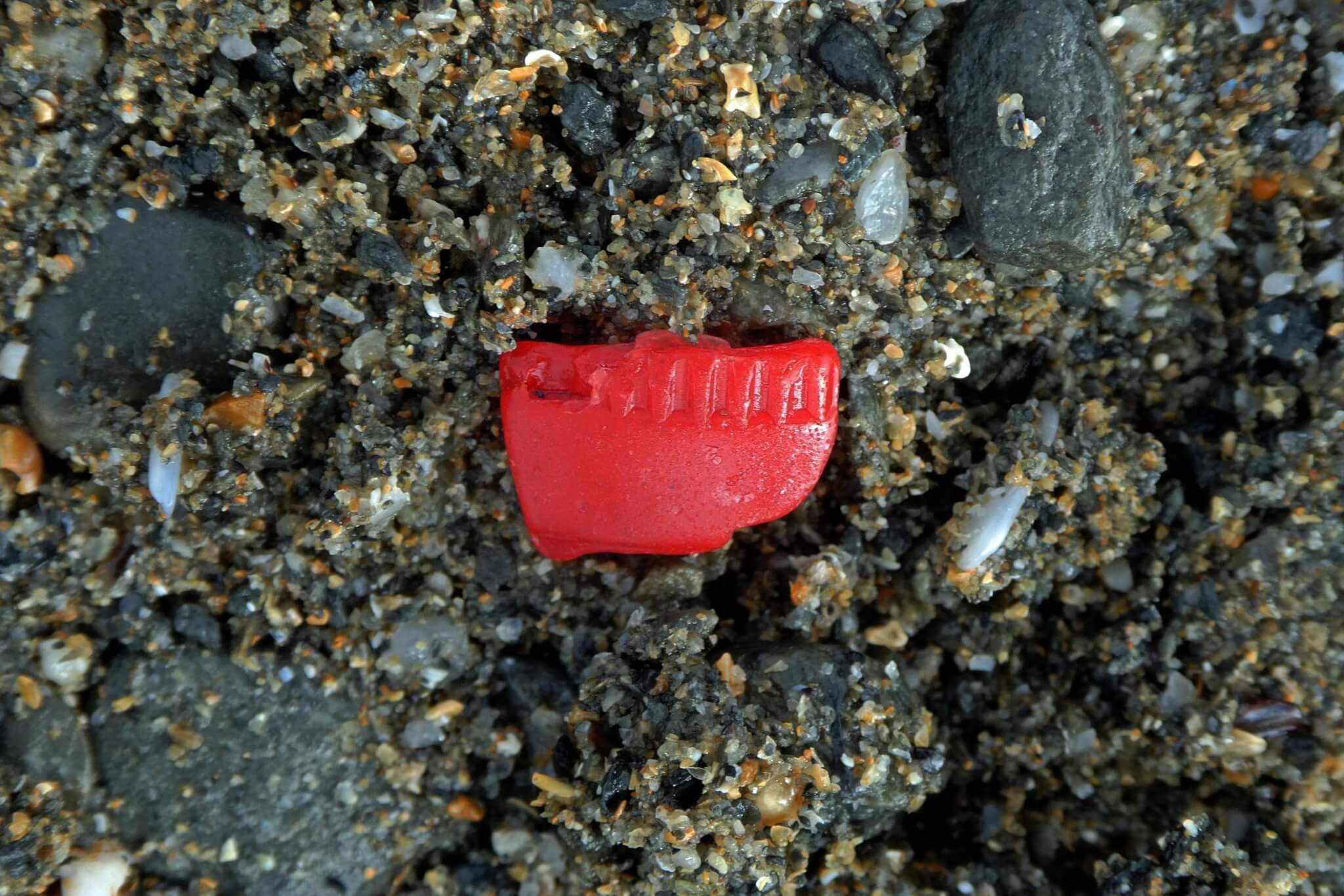 Red plastic fragment in the sand