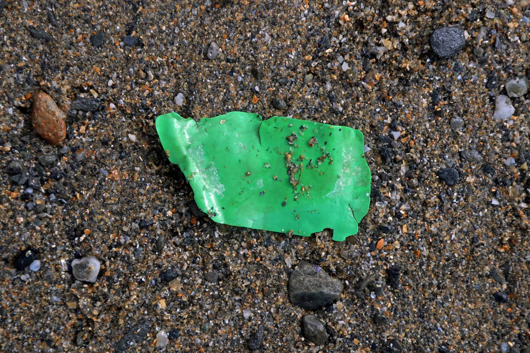 Green plastic fragment on the sand