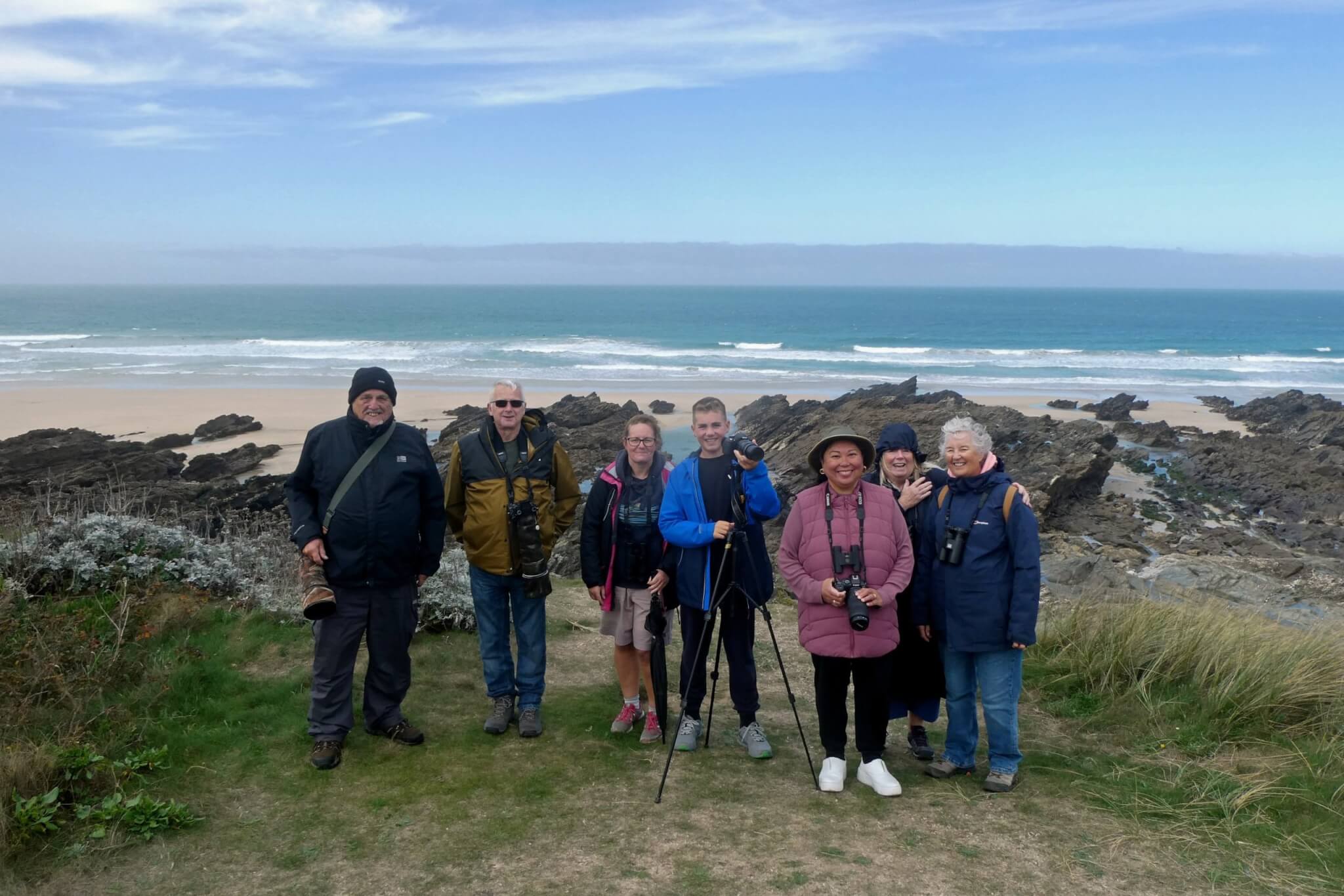 Birdwatching group standing on Towan Head with the beach and sea behind
