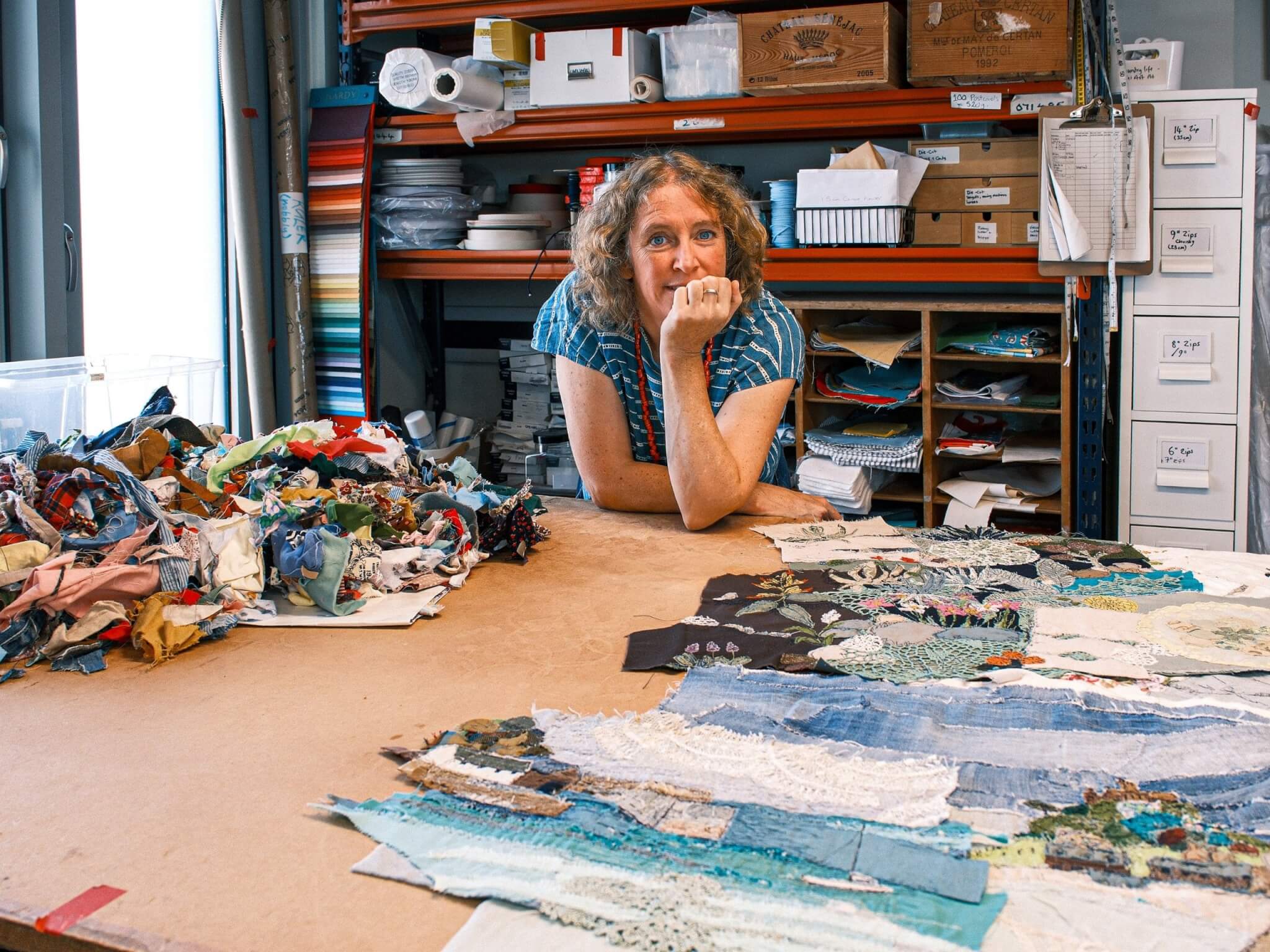 A maker at a work table covered in fabric pieces inside Pixel, Penzance