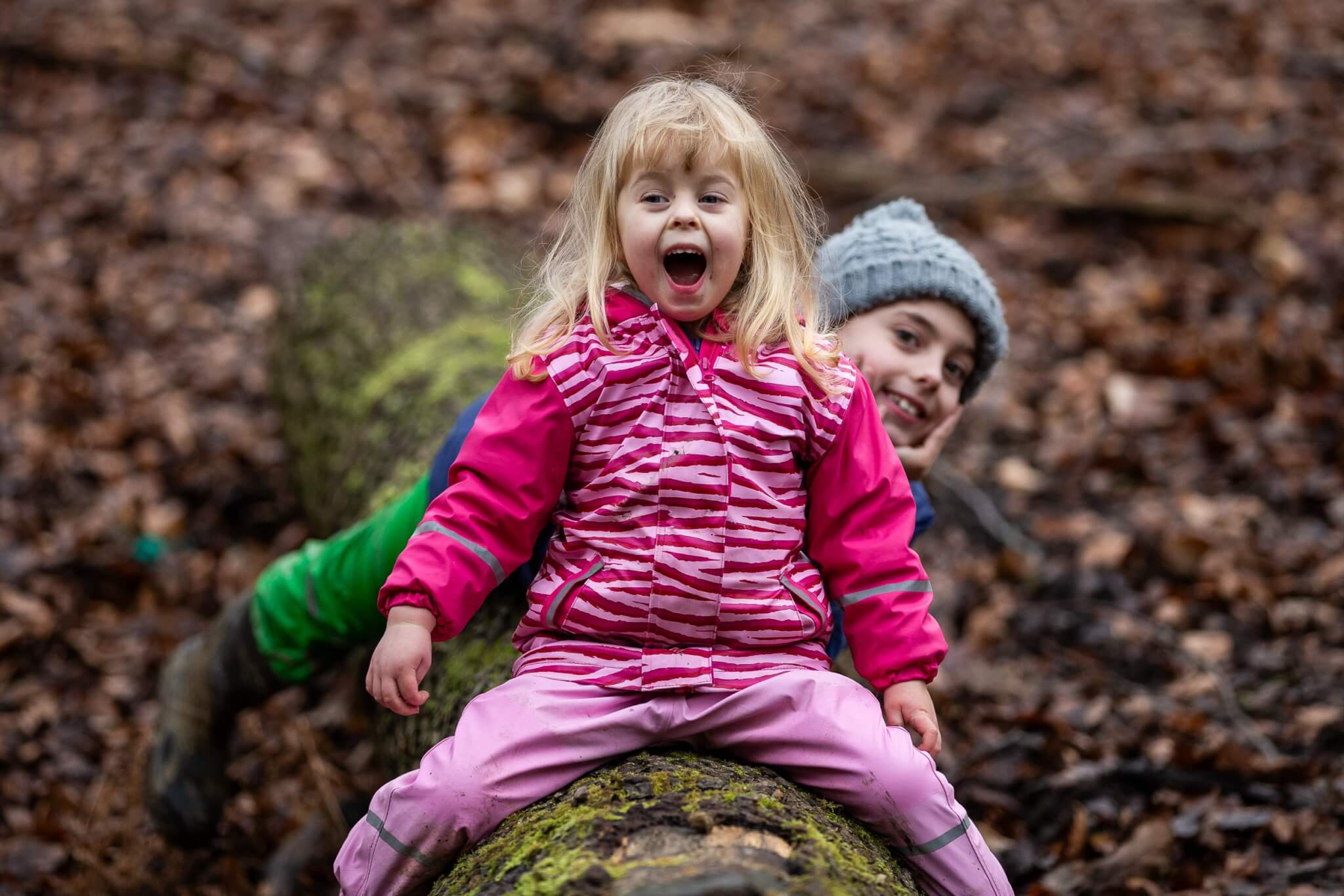 Children playing on a mossy log in the forest