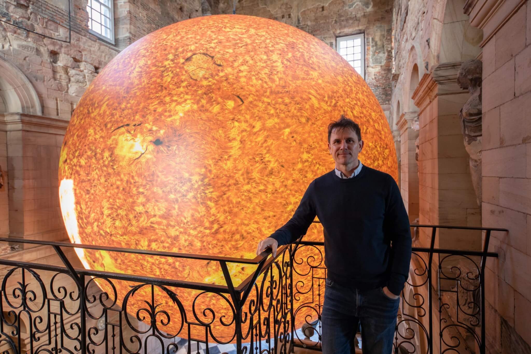 Artist Luke Jerram standing beside his Helios Sun artwork