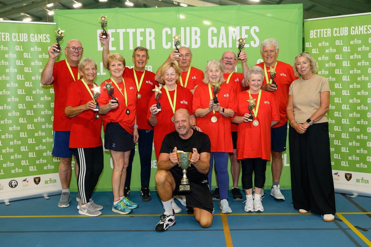 Red team with trophies, medals and a cup in front of Better Club Games banners