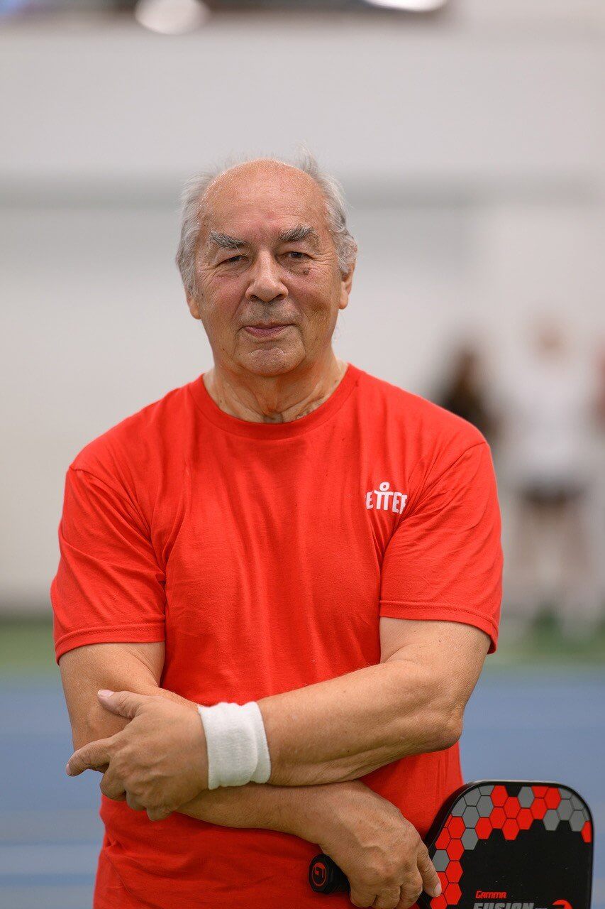 Pickleball player in a red Better shirt with arms folded