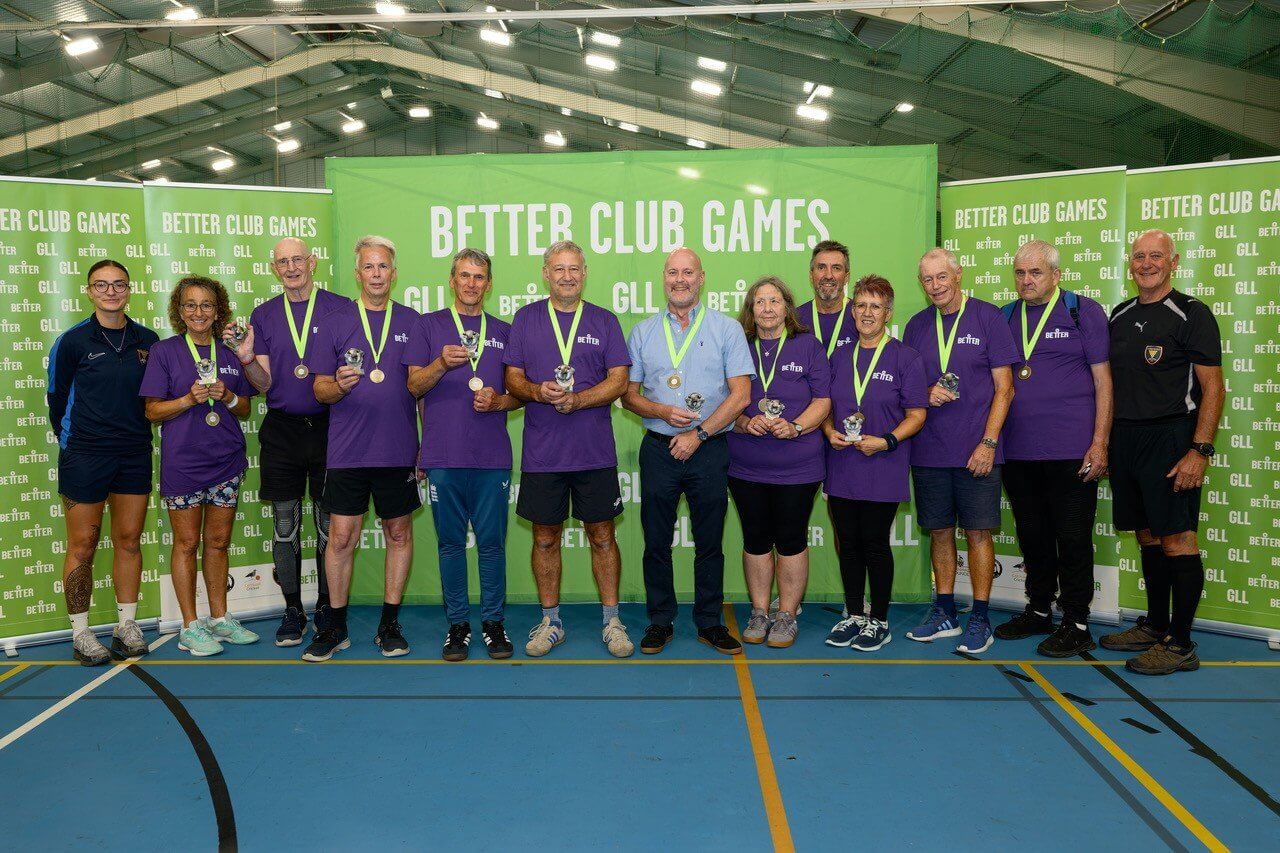 Purple team with medals and trophies in front of Better Club Games banners
