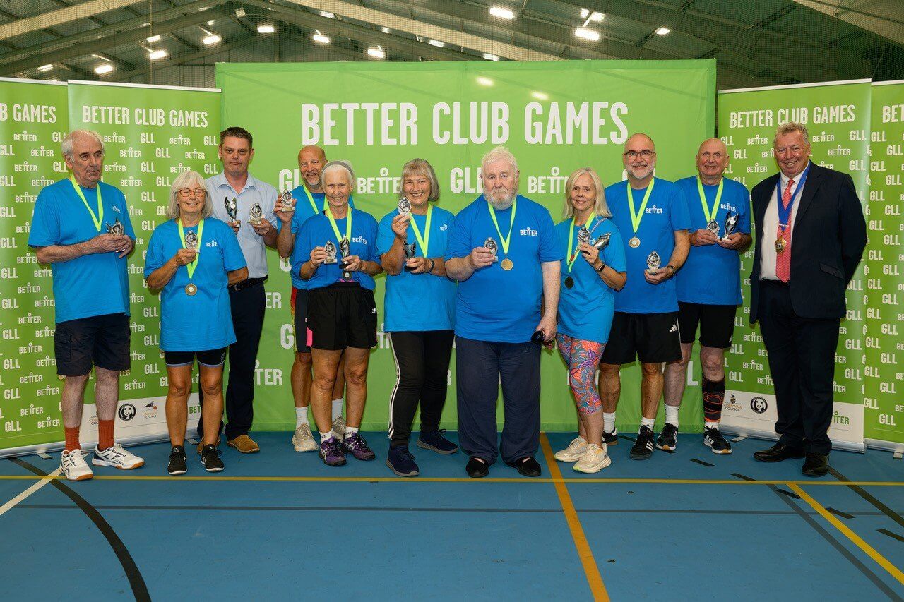 Blue team with medals and trophies in front of Better Club Games banners