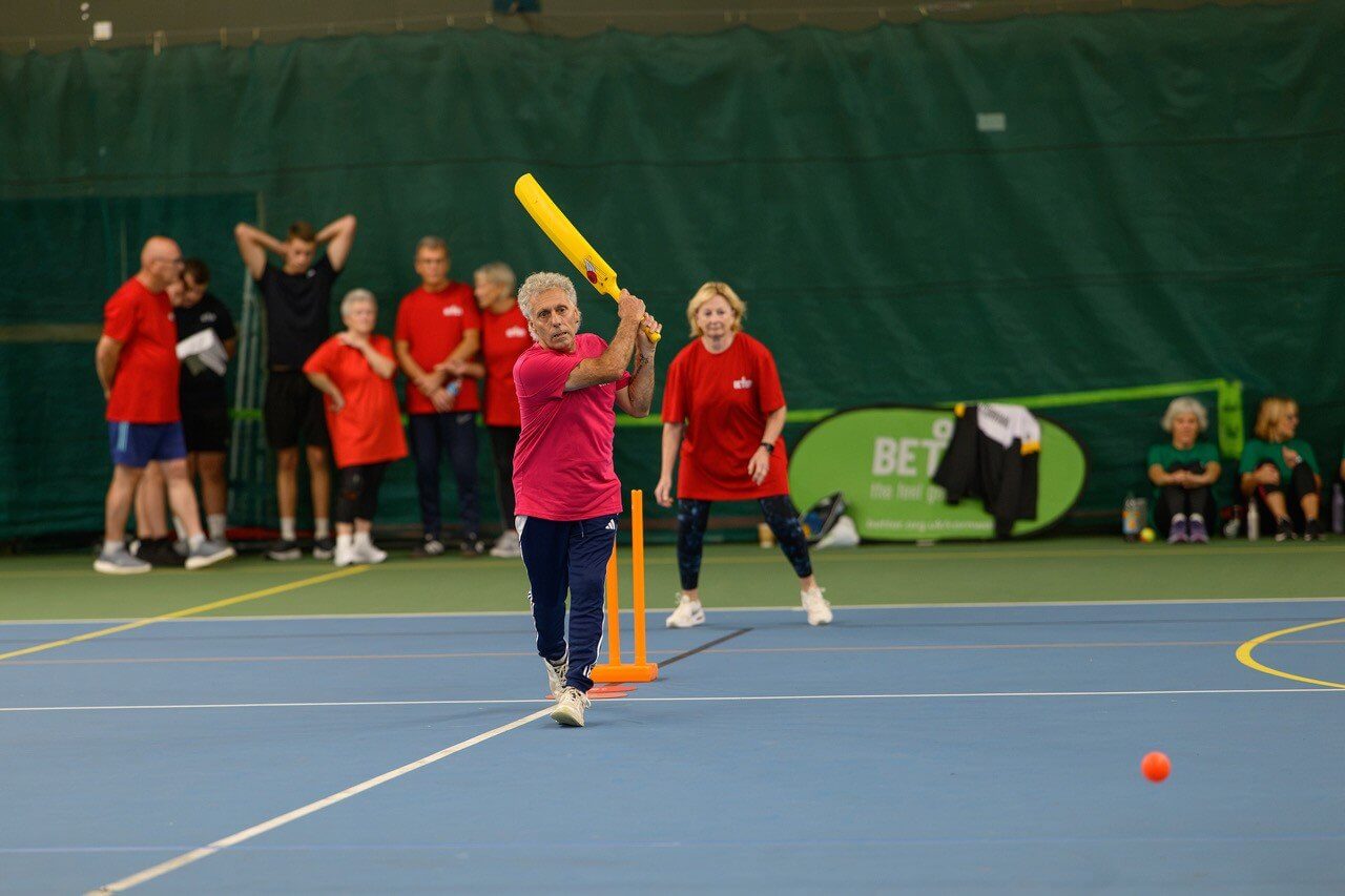Walking cricket batter mid swing at the Senior Club Games