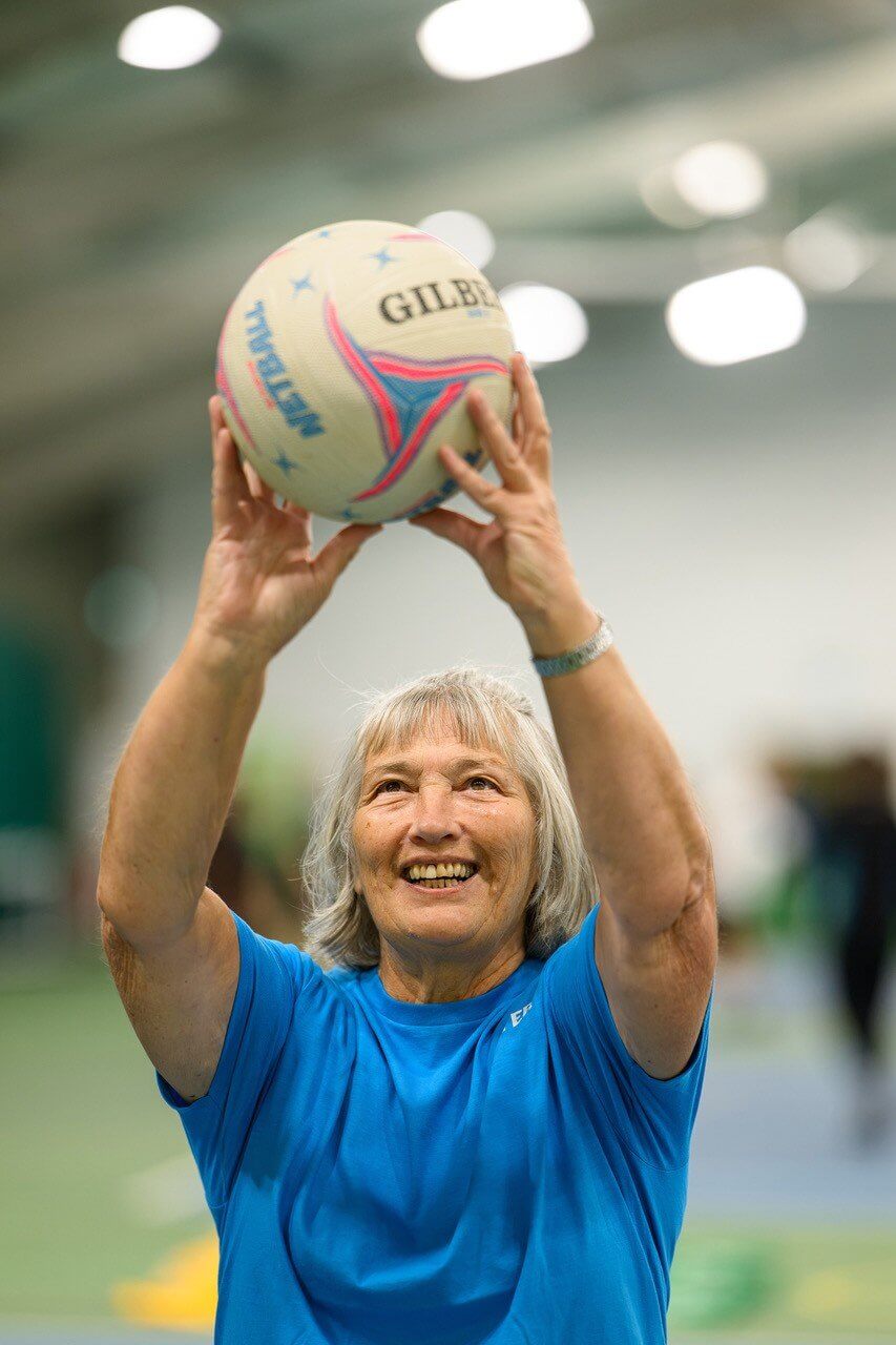 Walking netball player in a blue shirt lining up a shot