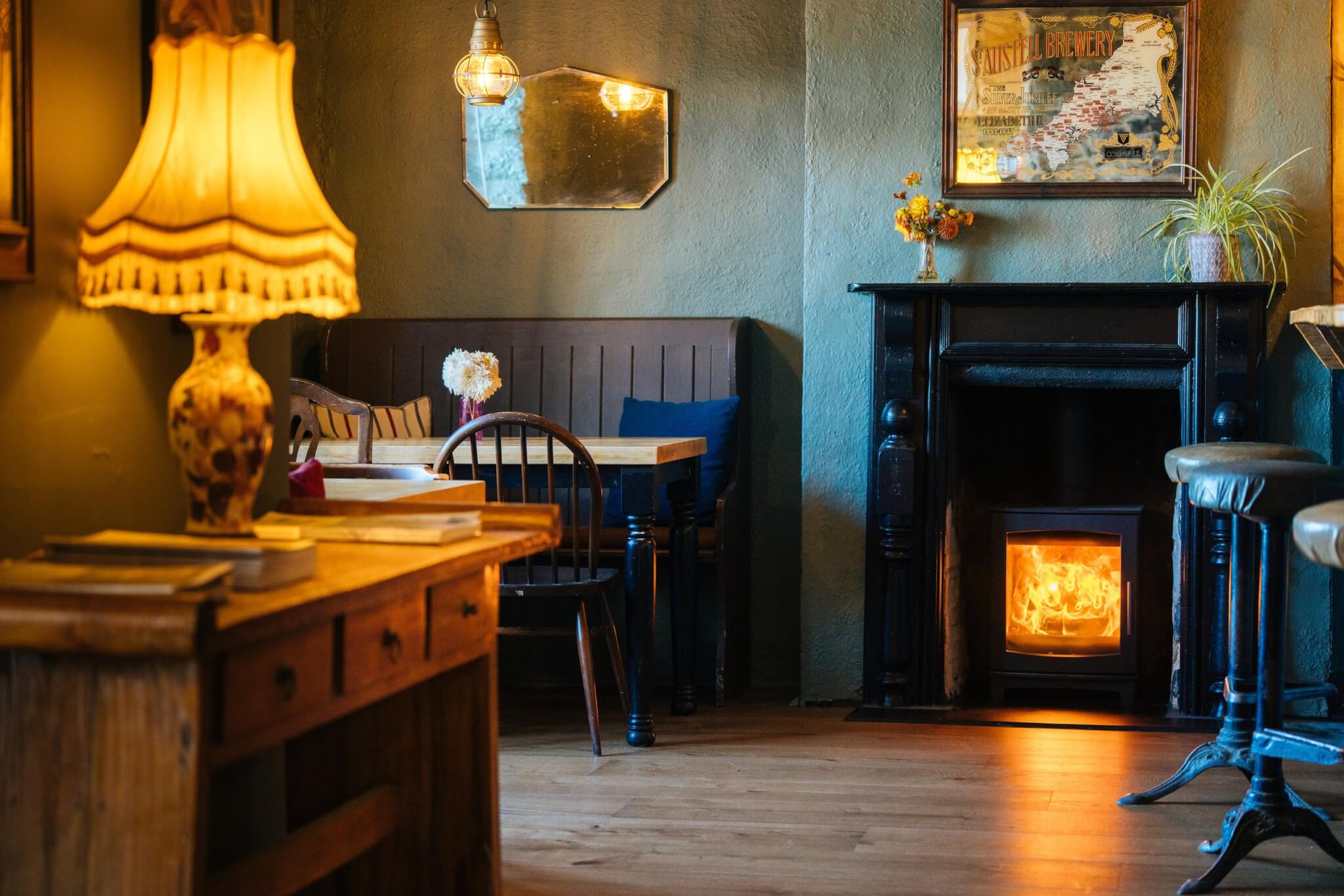 Lounge at the Red Lion in Newlyn with a lit log burner and table lamp