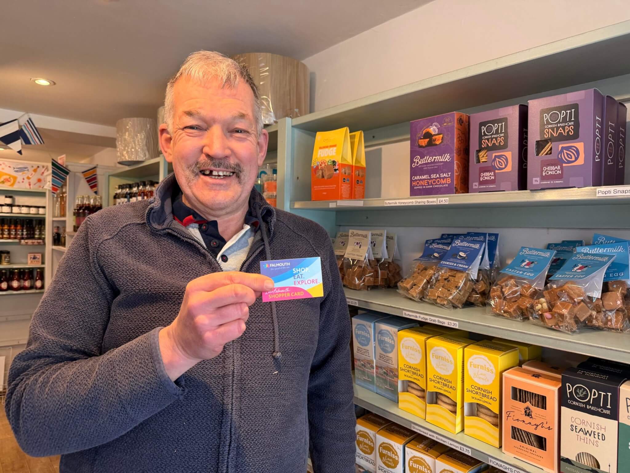 Rob from A Gift From Cornwall holding a LoveFalmouth Shopper Card in the shop