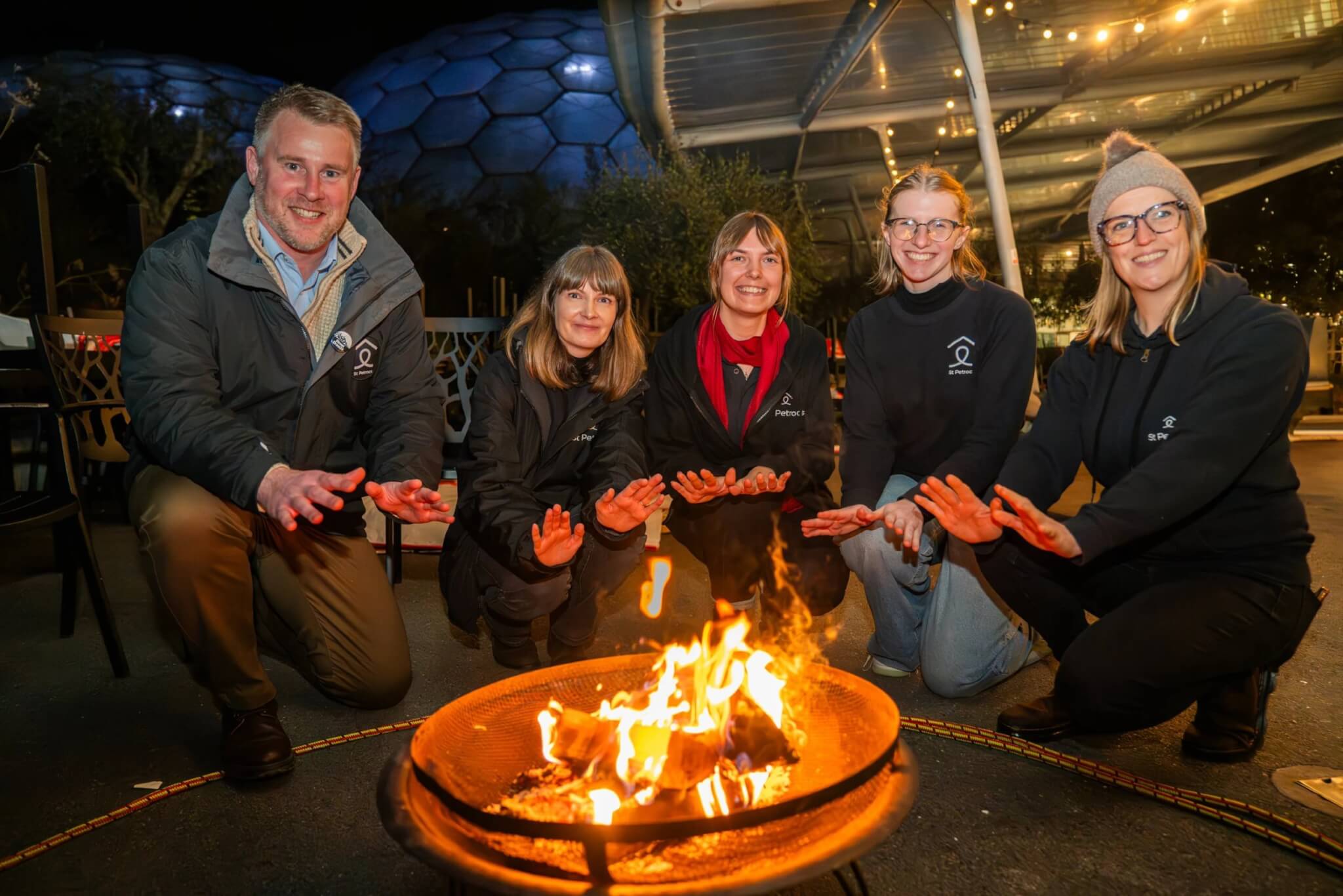Sleep Out supporters warming their hands around a fire pit at the Eden Project
