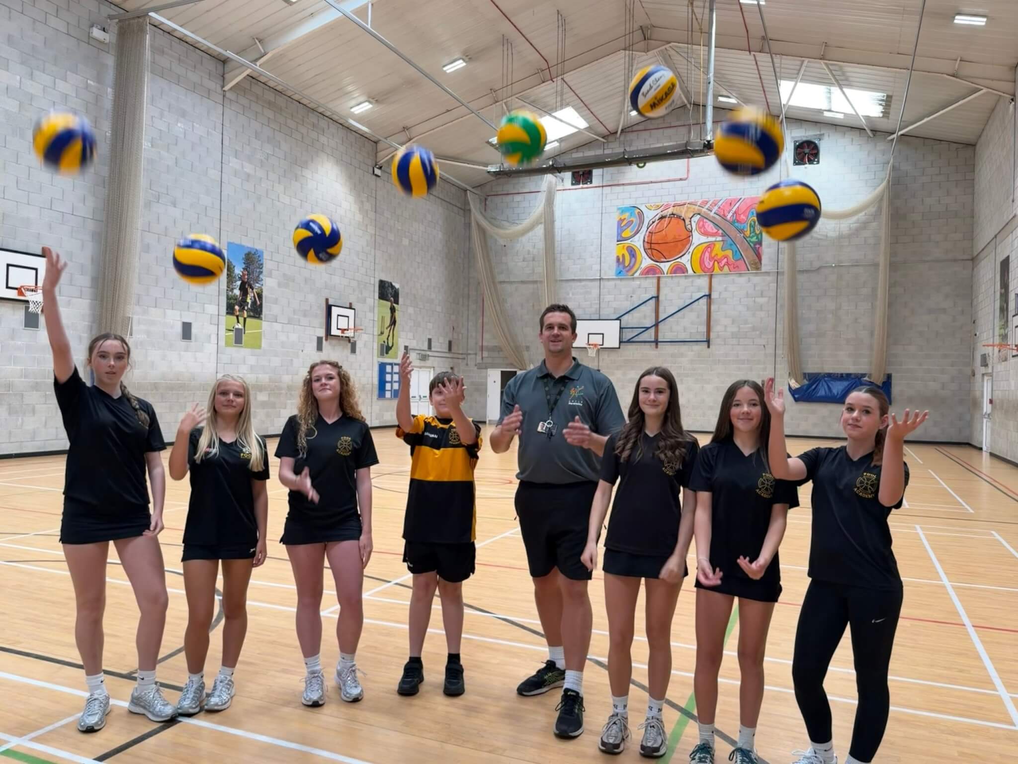 Matt Rogers and Pool Academy students throwing volleyballs in the sports hall