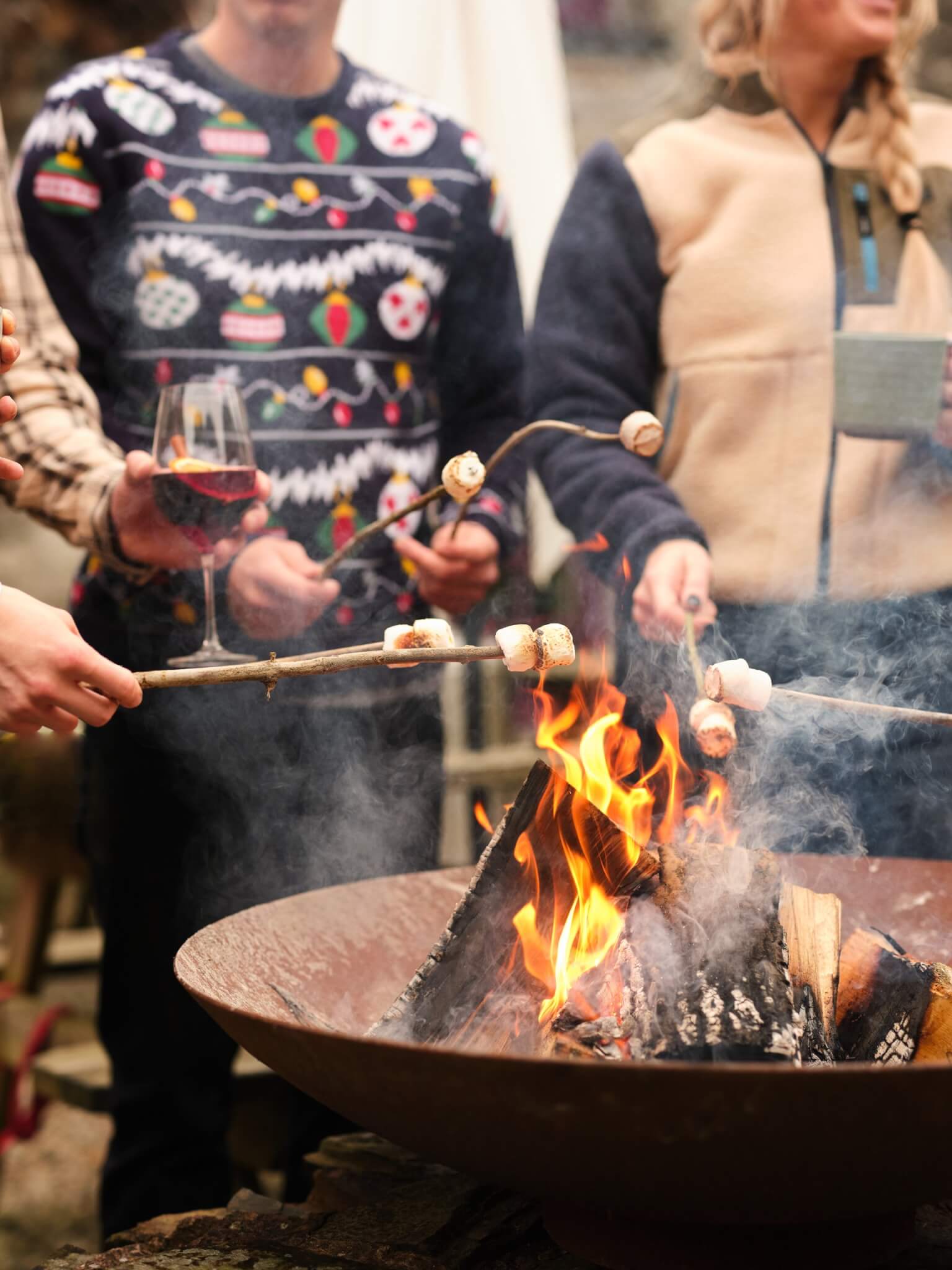 Guests toasting marshmallows over a fire pit