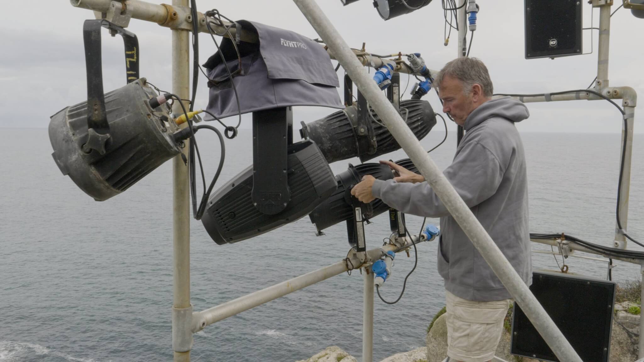 Simon Hutchings working on stage lighting rigs above the sea