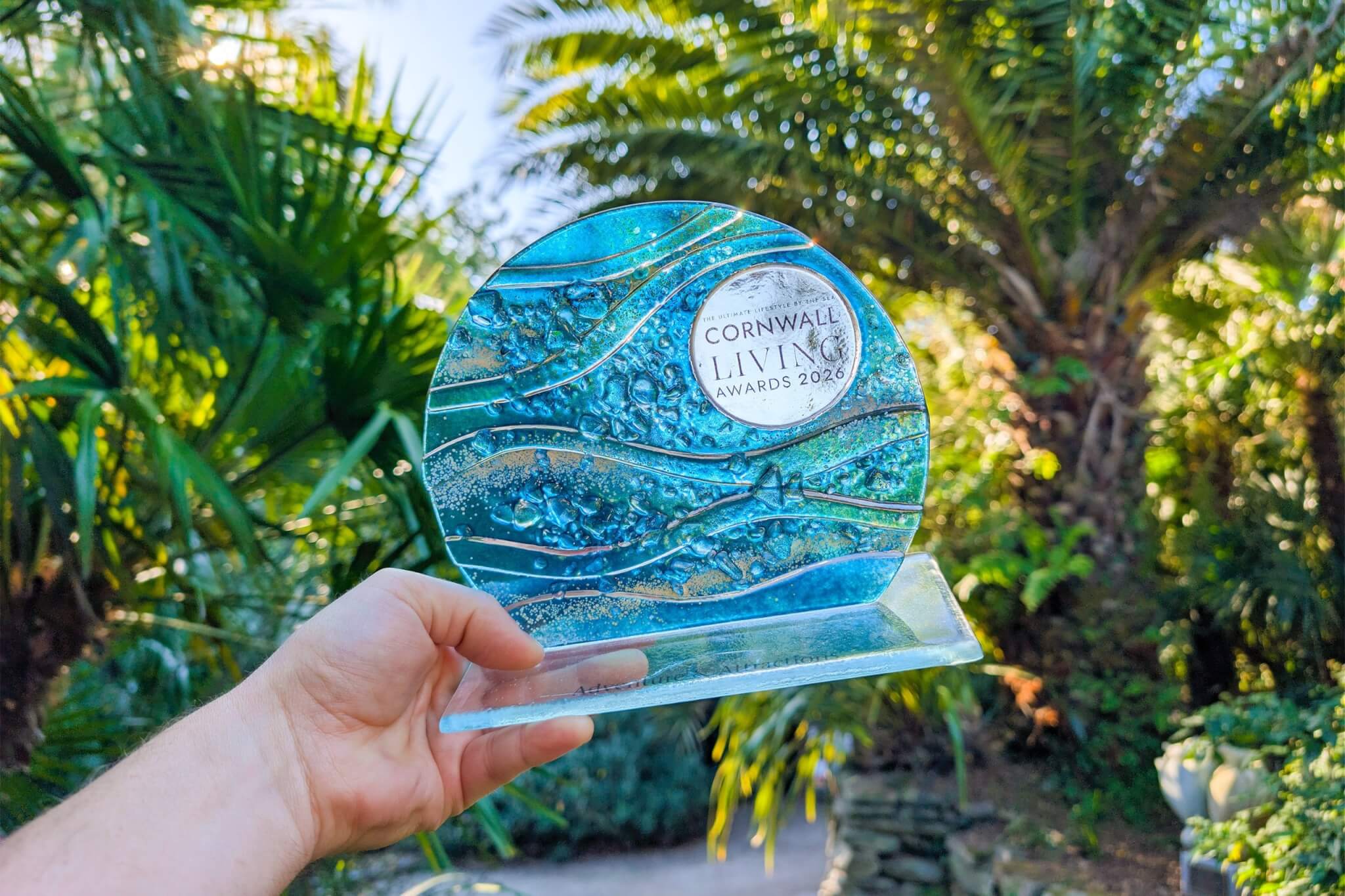 The Cornwall Living Awards 2026 trophy held up among palms at Trebah Garden