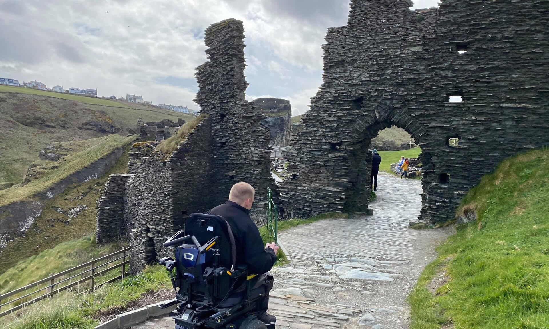 A powerchair user on the stone path at Tintagel Castle