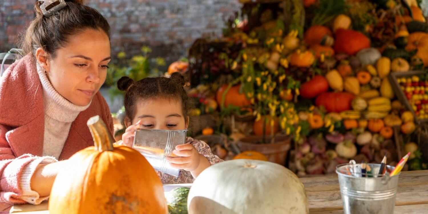 Mother and child at a Halloween activity table with pumpkins at Heligan
