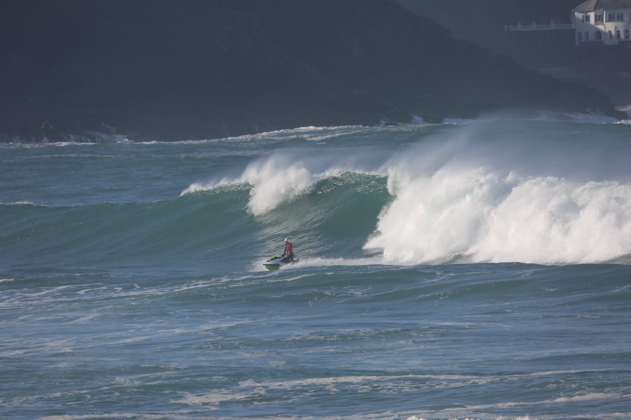 RNLI lifeguard on a rescue water craft in big surf at Fistral