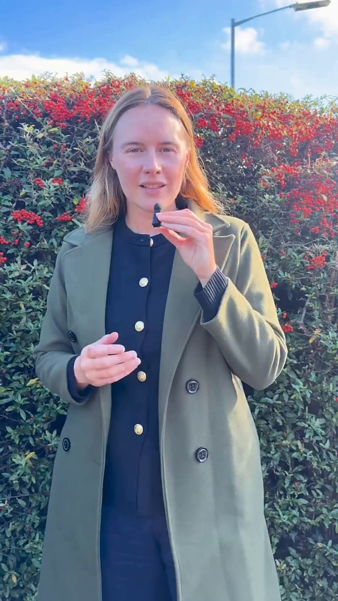 Anna Gelderd MP in front of a red berry hedge