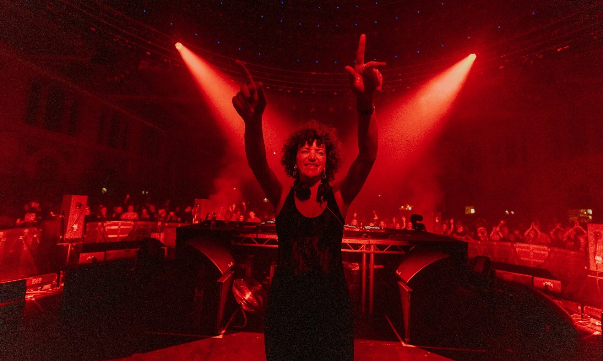Annie Mac with arms raised on stage under red lights