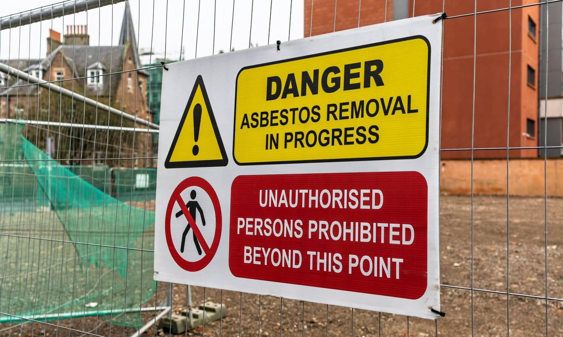 Danger asbestos removal in progress sign on a site fence