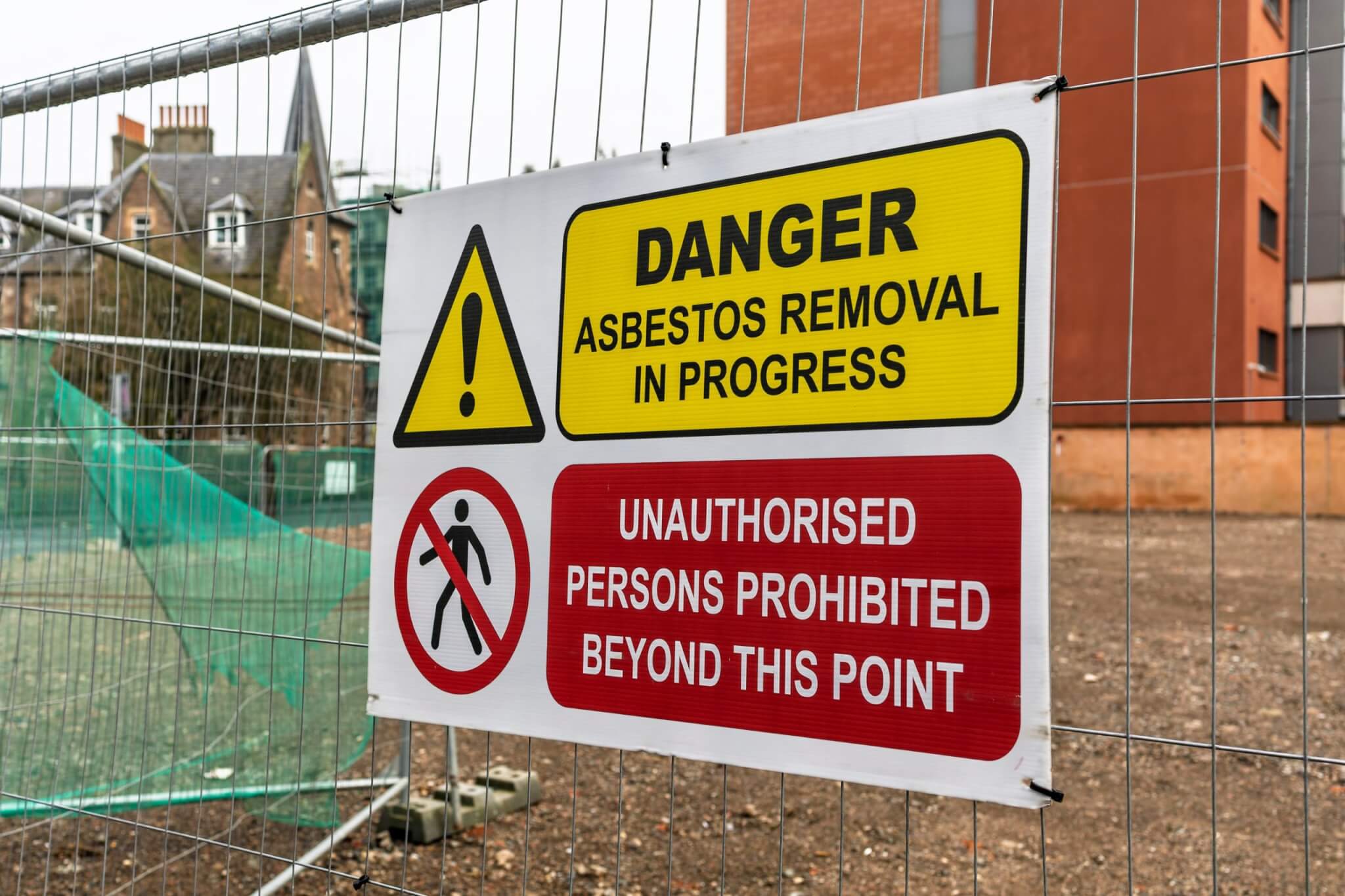 Danger asbestos removal in progress sign on a site fence