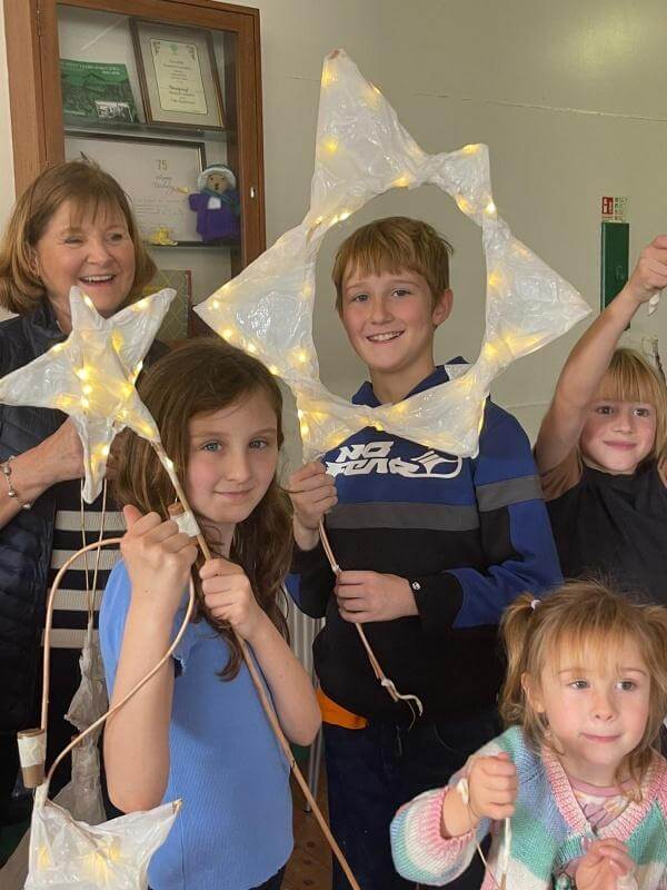 Children holding up lit star lanterns at a lantern making workshop