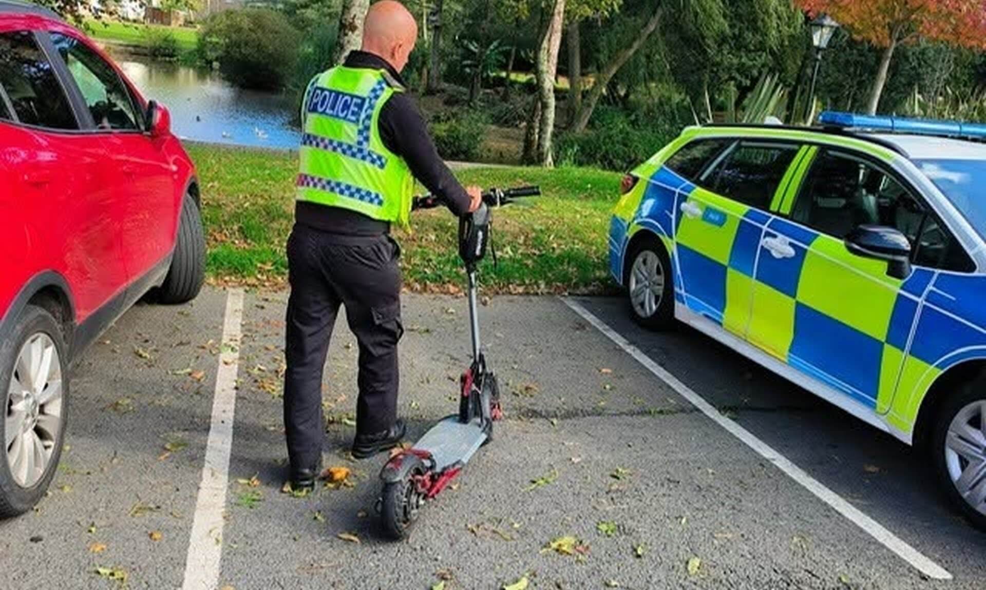 Police officer with a seized e-scooter beside a police car in Bodmin