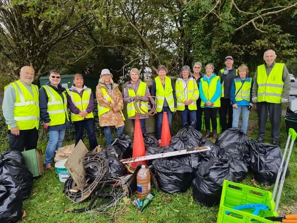 Bodmin Tidy it Team volunteers in hi-vis vests standing behind bags of collected litter