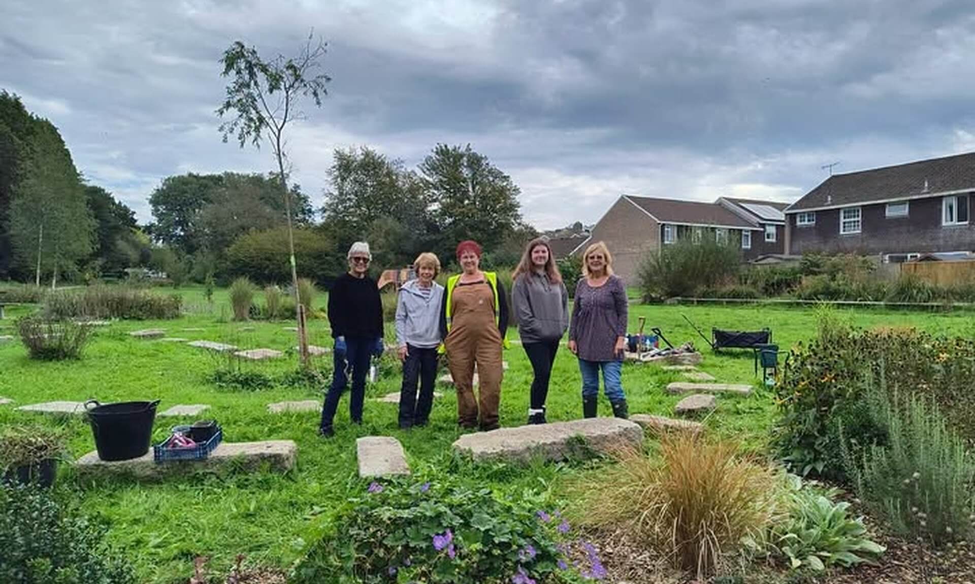 Five volunteers standing in Tredanek Meadow in Bodmin, with planted beds in the foreground