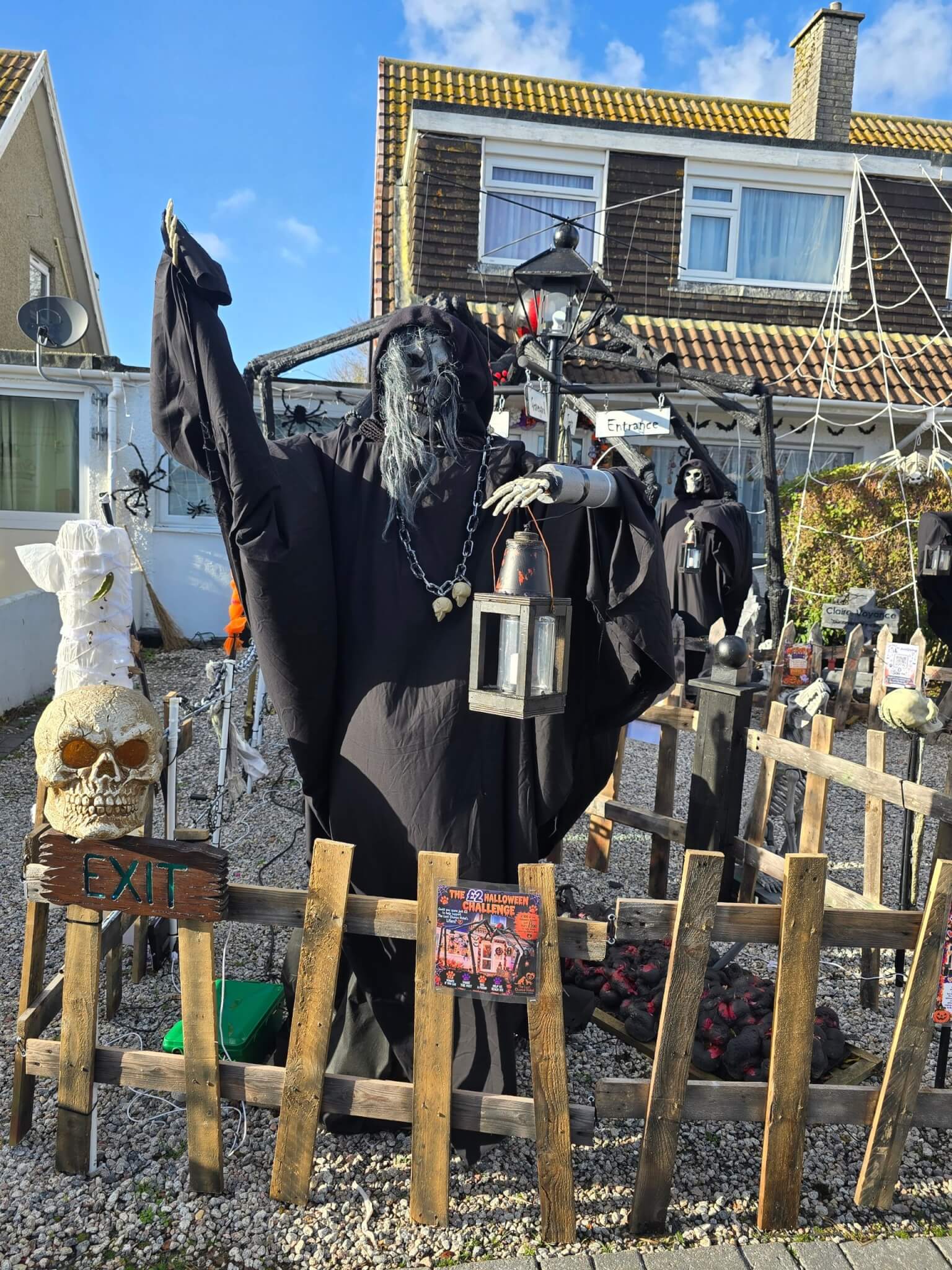 Hooded skeleton figure holding a lantern beside a wooden fence in the Boslowick Halloween garden