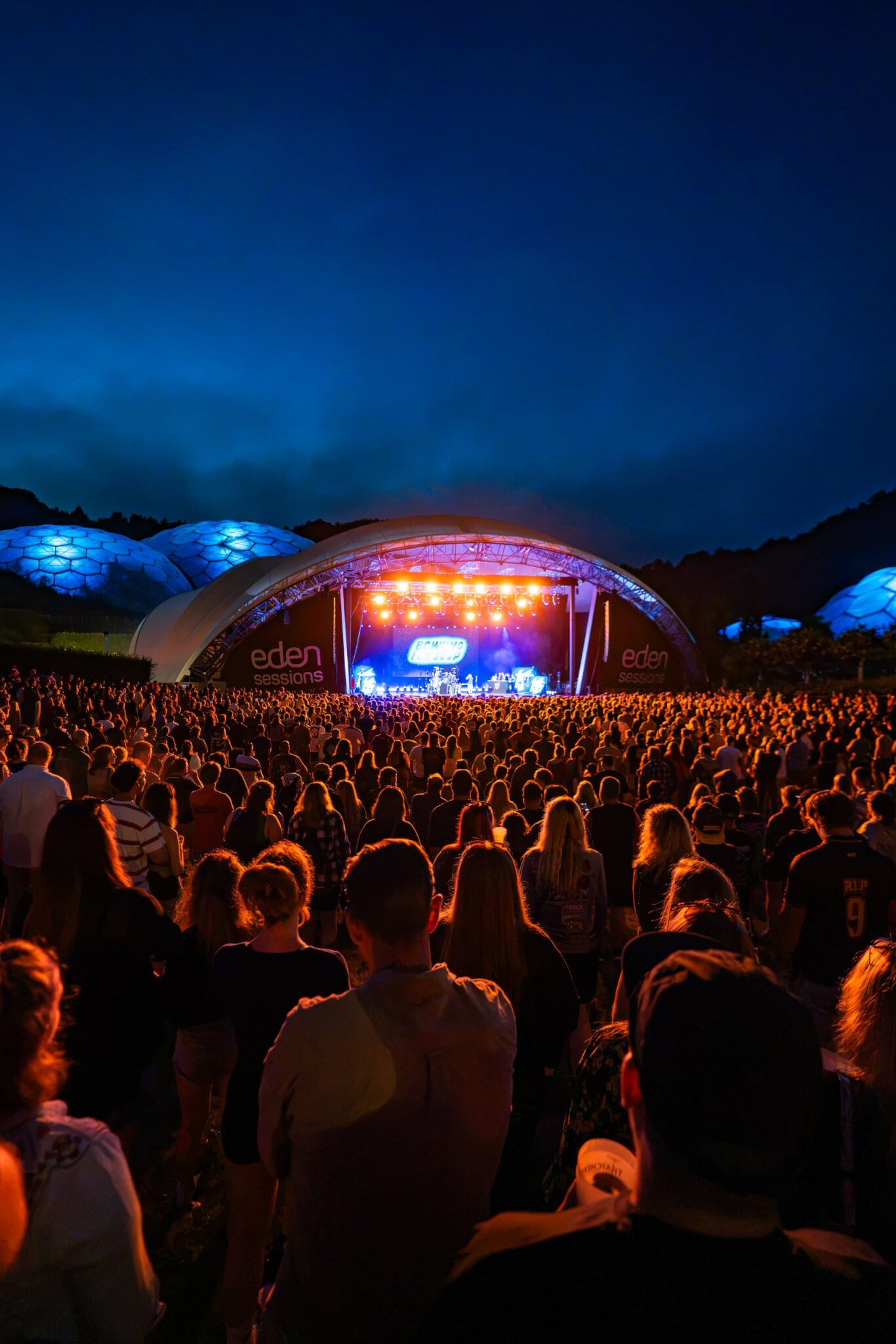 Packed Eden Sessions crowd facing the stage under a night sky