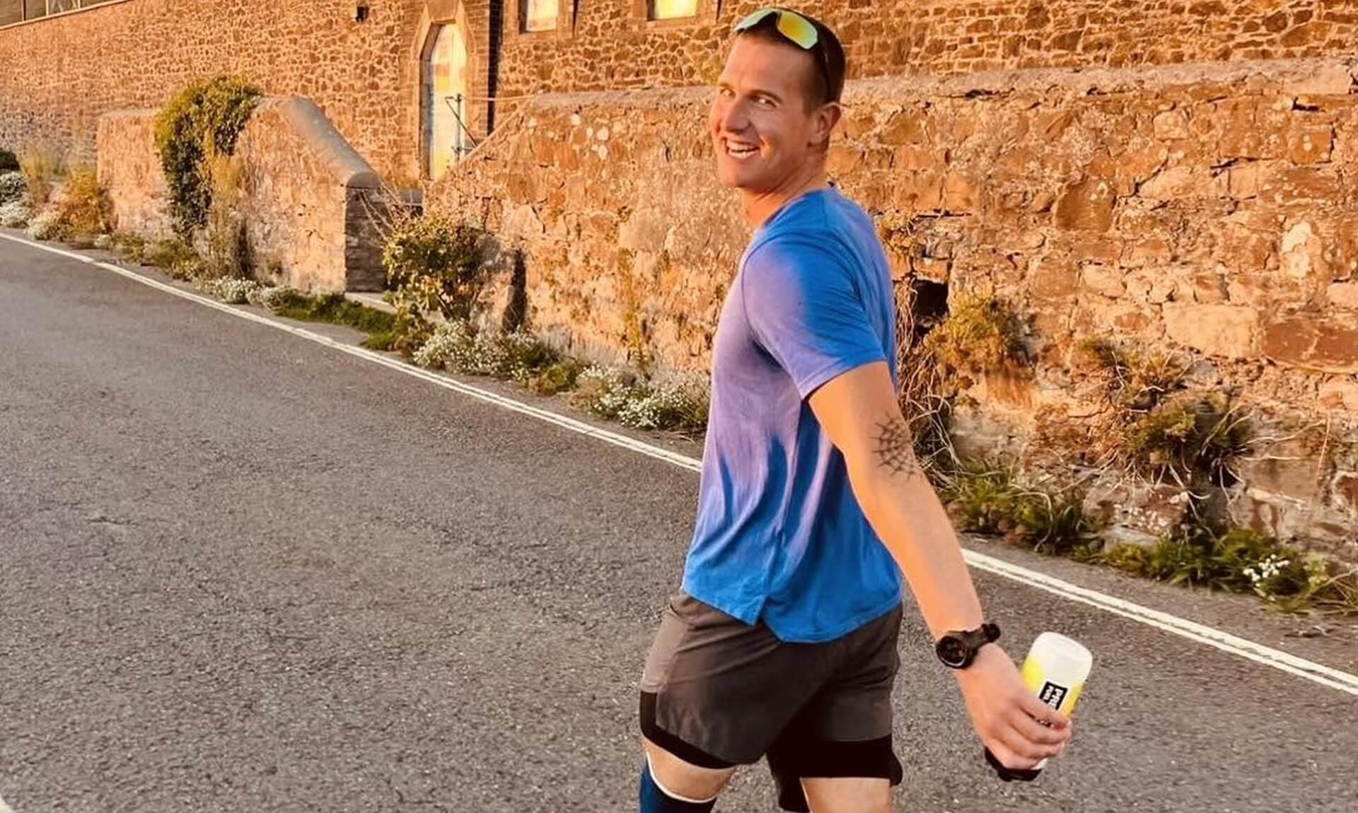 Runner in a blue t-shirt smiling during the 25-hour challenge in Bude