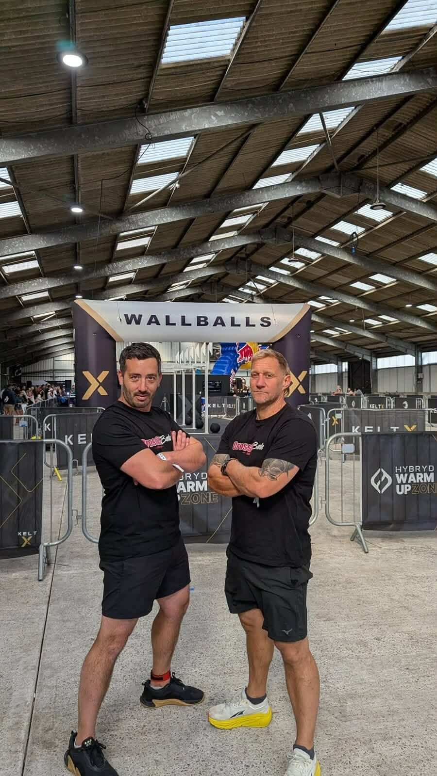 Two Bude lifeboat crew members with arms folded in front of the KeltX wall balls station
