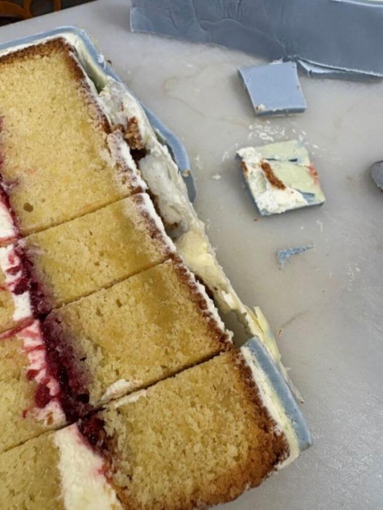 Cut wedding cake with plastic visible beneath the icing
