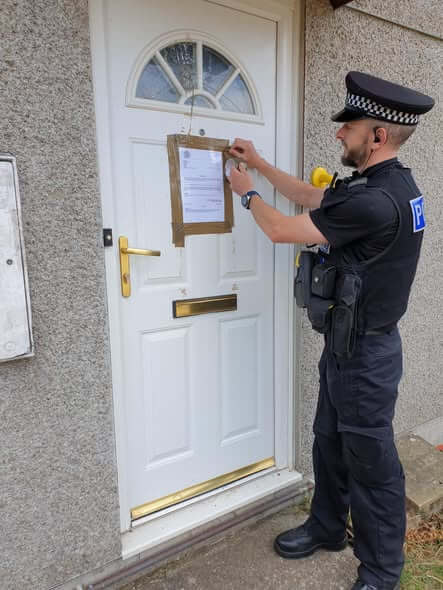 An officer puts up a closure order notice in Camborne.