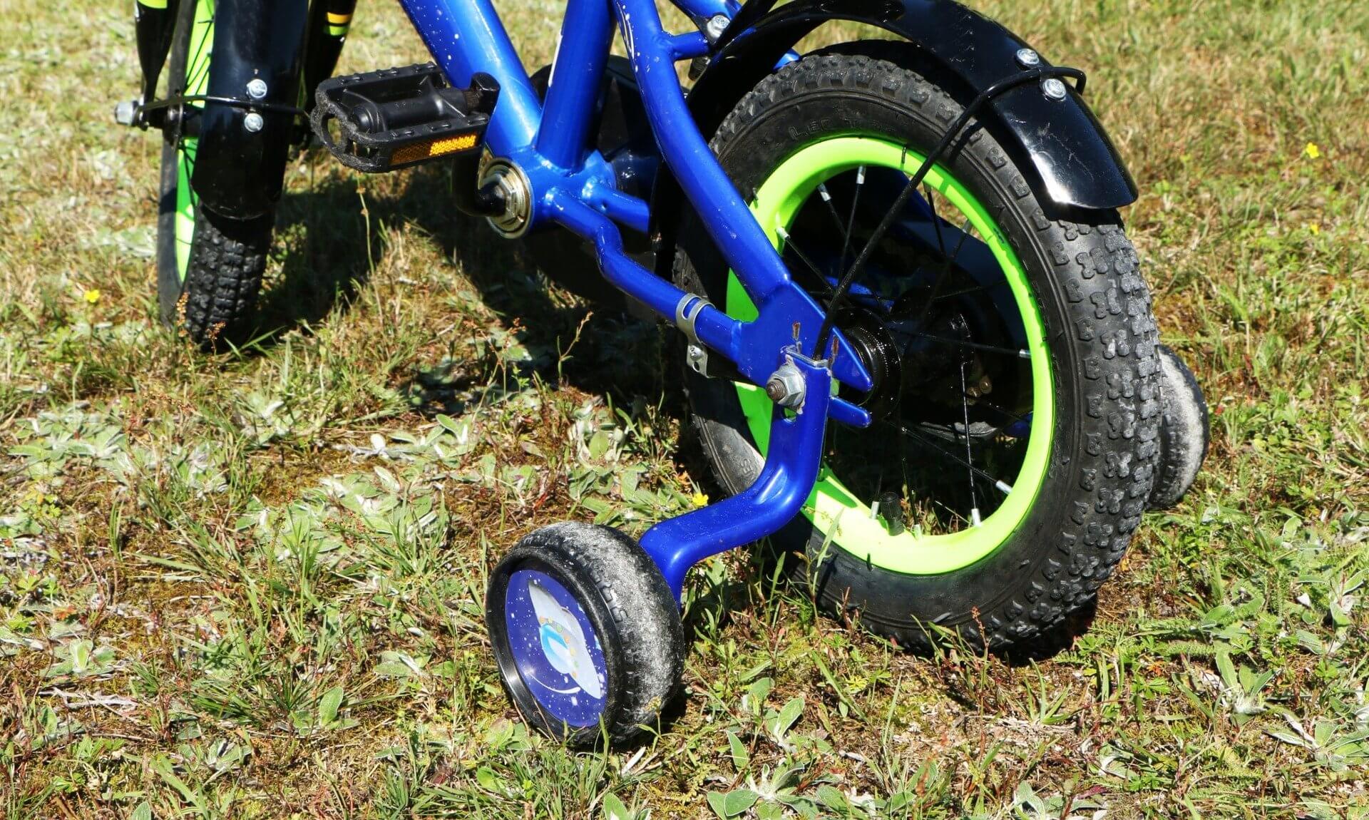Child's blue bike with green wheels and stabilisers on grass