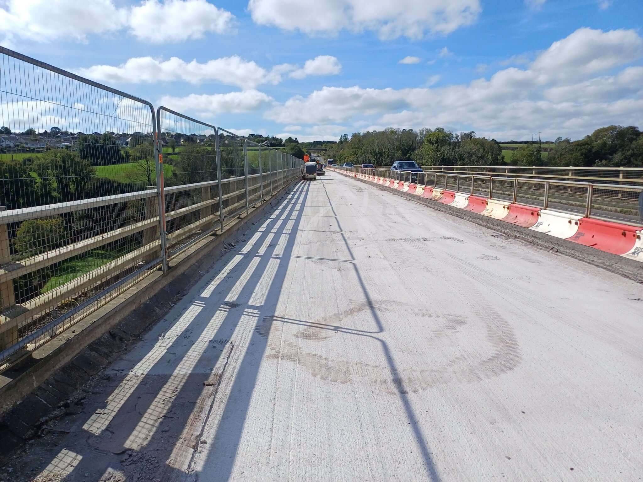 Bare concrete bridge deck on the Camel Viaduct at Wadebridge with safety fencing and traffic passing on the other side
